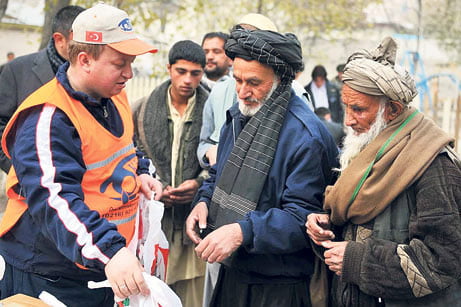 A Kimse Yok Mu relief worker delivers supplies to two elderly Afghanmen