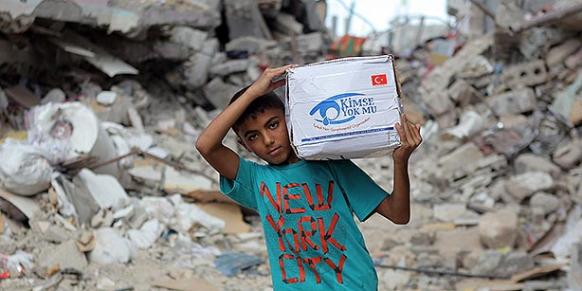 A Palestinian kid carries an aid package delivered by Kimse Yok Mu? charity organization in Gaza. (Photo: Today's Zaman, Mehmet Ali Poyraz)