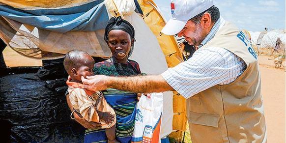 A Kimse Yok Mu volunteer hands out sacrificial meat to Somali refugees taking shelter in a Kenyan refugee camp on Eid al-Adha. (Photo: Today's Zaman)